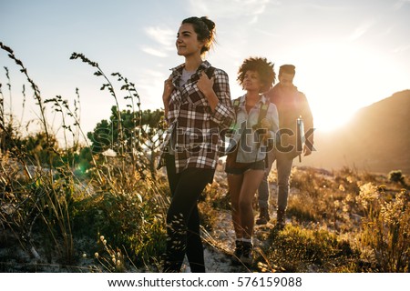 Group of friends on country walk on a summer day. Young people hiking in countryside. Royalty-Free Stock Photo #576159088