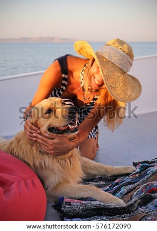 Beautiful woman in a hat with labrador nice dog on a yacht with sea landscape