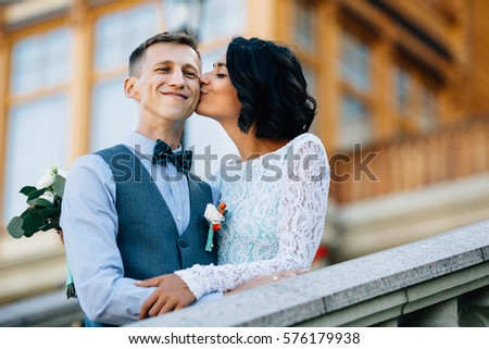 Bride kissing happy groom in cheek at wedding day