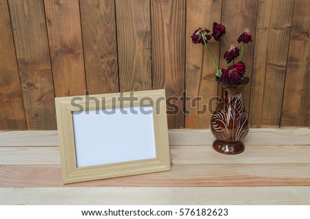 Frame on a wooden background, and a vase of roses, dried , select focus.