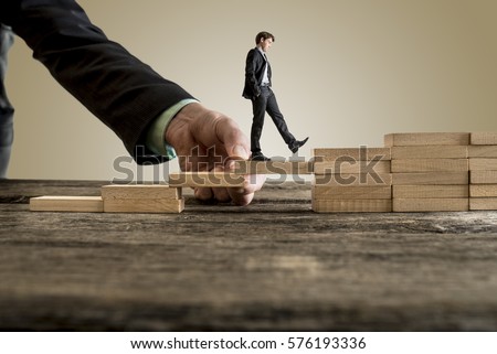 Businessman in business suit walking up steps, while the hand of other man helping him in a conceptual image of insurance, assistance and support. Royalty-Free Stock Photo #576193336
