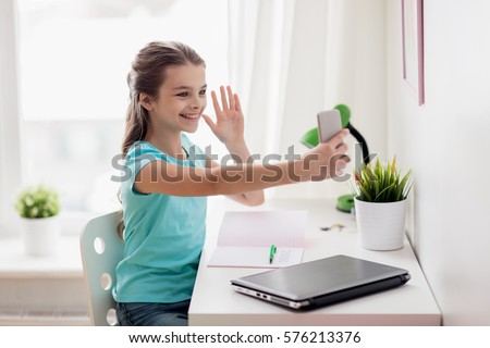 people, children and technology concept - girl with laptop computer and smartphone taking selfie or having video call at home