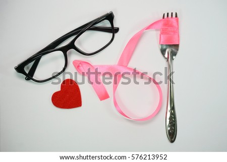 Healthcare and Medicine Concept - A pink ribbon, eyeglasses, read heart shape and a fork isolated on a white background.Breast cancer awareness pink sign symbol for help illness people