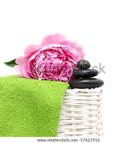 Spa treatment. Black stone, green towel, flower. Focus on the pebble