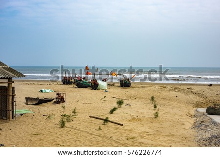 Traditional Vietnamese boats, with the country's flag. on the shore of the beach, among the debris. littered coastline. South China Sea. the remains of boats and crab traps thrown out to the shore