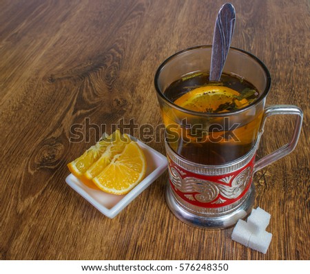 Vintage, a very old, rusty ornate metal style glass holder with glass, herbal tea with lemon and sugar cubes. background on wood