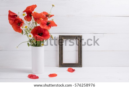 Red poppies bouquet in vase and photo frame on background of white wooden planks in scandinavian style