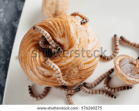 Cream cakes souffle on a plate with worms (zofobas) on it