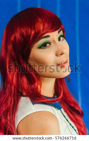 the girl of Asian appearance , in a red wig and blue dress . the anime style. Girl posing on blue background