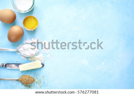 Ingredients for baking - eggs,flour,sugar,butter,milk on a light blue concrete,stone or slate background.Top view with space for text. Royalty-Free Stock Photo #576277081