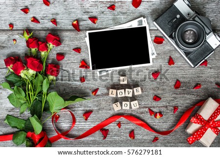 i love you inscription with blank photo frame, vintage retro camera and red roses flowers and gift box on rustic wooden background. top view. valentines day background