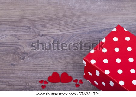 Gift for Valentine's day and red hearts on a wooden  background