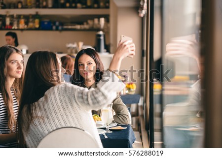 Girls happy to be together after long time. Eating drinking having fun at their favorite restaurant, taking many selfies, pictures to put online, for celebrating their reunion.