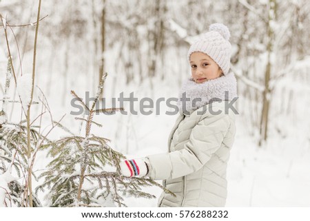Beautiful girl playing in a winter forest. The child have a rest in the open air in winter
