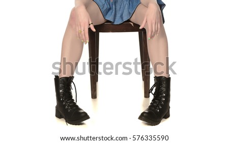 beautiful woman legs wearing mans boots siting on old chear posing on white background.