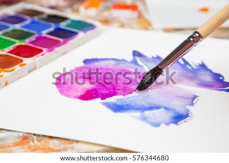 Closeup of paintbrush on the picture, abstract color draft at the table with palette