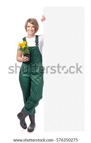 young smiling woman professional gardener with flower standing next to the banner with empty copy space isolated on white background. advertisement blank board. gardening service and business concept