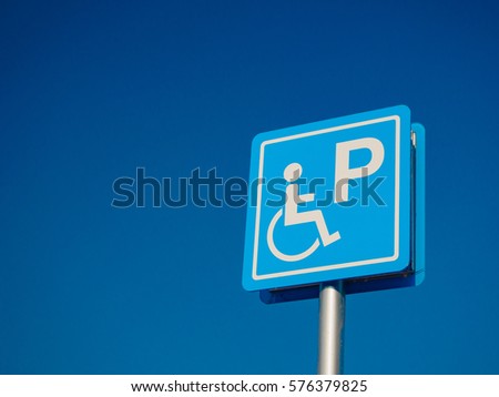 Disabled parking space and wheelchair way sign and symbols on a pole warning motorists
