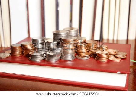 Many stacks of coins in various sizes and valued,Coin on a book cover red,The success of literacy education , Financial and commit business concept
