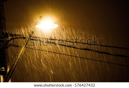 Street Lamp II: A street lamp illuminates the snow as it falls. Royalty-Free Stock Photo #576427432
