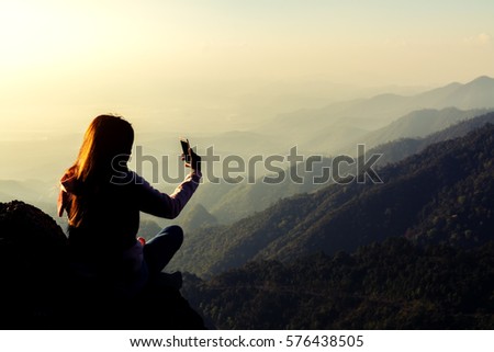 silhouette women sitting and use smartphone selfie on mountain