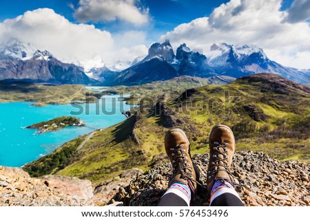 Legs of traveler sitting on a high mountain top in travel. Freedom concept. Patagonia, Chile Royalty-Free Stock Photo #576453496