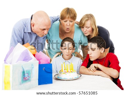 Family helps a little boy blow out his birthday candles.  White background.