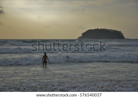 Woman with wave and gold light in sunsets sky, Karon beach, Phuket, Southern of Thailand, 
