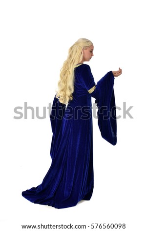 Full length portrait on a beautiful young woman with long blonde hair, wearing a blue velvet medieval gown. standing pose, isolated on white background.