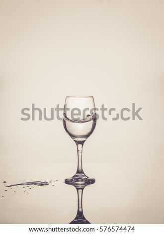 Water splashes from the glass isolated on grey background. Water in the glass. Glass is half full or half empty concept