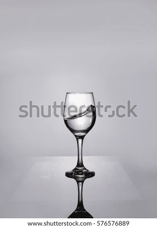 Water splashes from the glass isolated on grey background. Water in the glass. Glass is half full or half empty concept