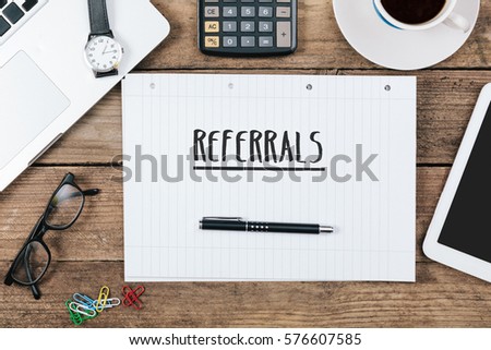 word referrals on notebook, Office desk with electronic devices, computer and paper, wood table from above, concept image for blog title or header image. Royalty-Free Stock Photo #576607585