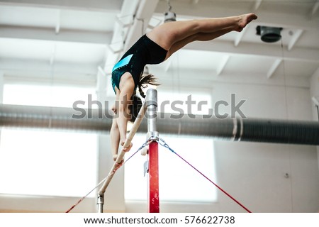 girl athlete gymnast exercises on uneven bars Royalty-Free Stock Photo #576622738