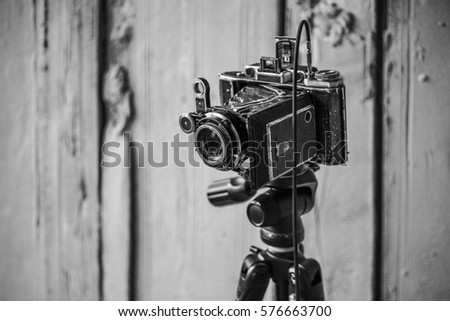 Vintage folding camera on abstract background. Black and white image.