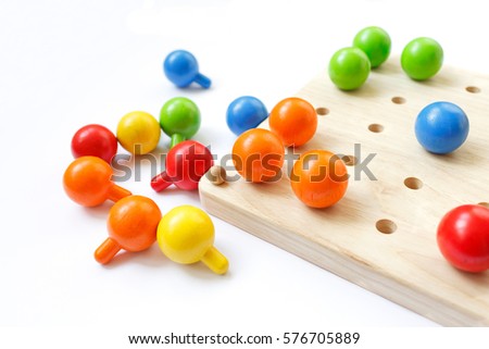 Colored pegs board, wood beads on white background