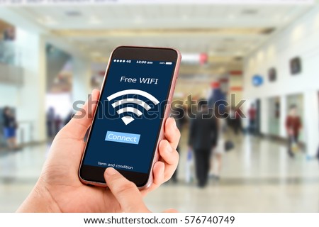Free wi-fi concept.Hands holding mobile phone on blurred business man walking Royalty-Free Stock Photo #576740749