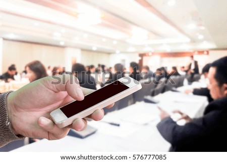 Man use mobile phone, blur image of conference room as background.