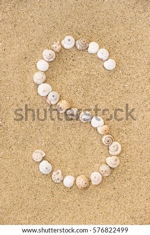 Summer alphabet letters, letter S made of seashells on sand.