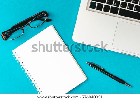 working desk, Laptop and other office supply on blue background, top view