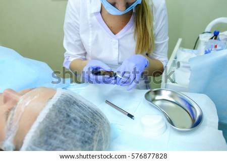 Blonde girl European appearance, professional engaged in reconstruction of eyebrows responsibly preparing to start work mikrobleyding eyebrows, eyebrows customer focused prepares women to paint