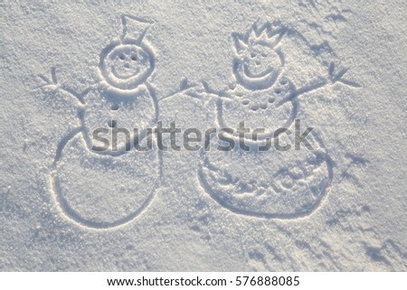 Loving couple snowman and snow - girl drawn in the fresh snow in sunny winter day. 