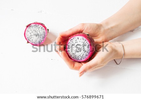 Female hands and Juicy pink pitaya on wooden table.