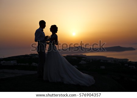 Newlyweds at sunset. On the background of the sky and sights of the Greek Islands.