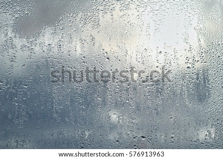 drops water on wet glass window background in rainy day. rain outside window. summer or autumn rainy season. abstract texture of raindrops close up.