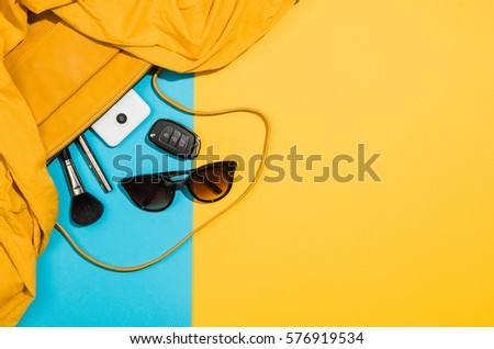 Woman's accessories flat lay on colorful background. Top view Blue and yellow pastel colors with copy space around products. Horizontal image or photograph.