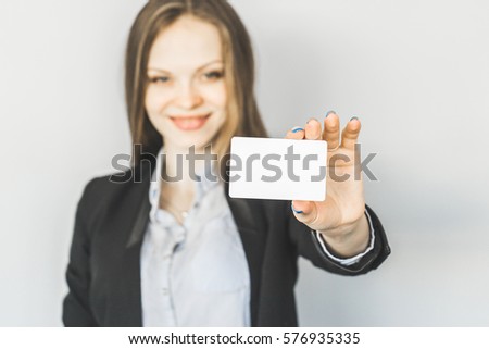 Pretty young blurred office woman shows business card. Woman out of focus shows white blank