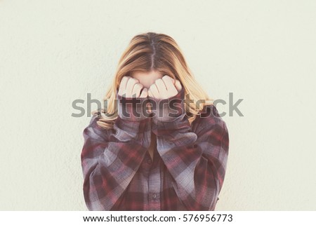 Young woman with hands over face in retro style portrait concept of fear shame and shyness, vintage retro color effect style Royalty-Free Stock Photo #576956773