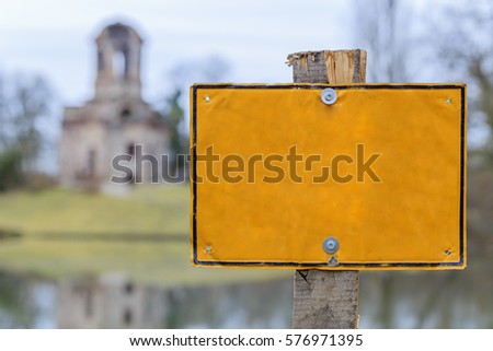 Blank yellow sign on Ruins and lake shore  background, text place