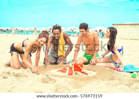 Multiracial group of best friends play on the beach sand race balls - Happy multicultural young people having fun by childish game on summer vacation - Enhanced cyan filter as old instant camera look