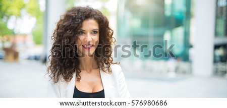 Smiling woman walking in a city, Wide image
